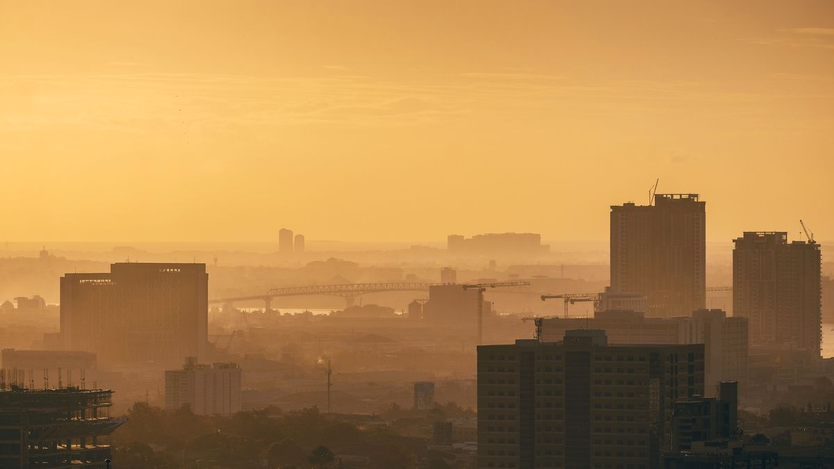 Hazy golden sunrise over Cebu City, with cranes on the towers and the Mactan bridge in the distance.